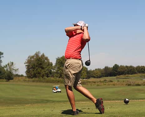 Golfeur en plein swing sur un terrain de golf par temps clair.