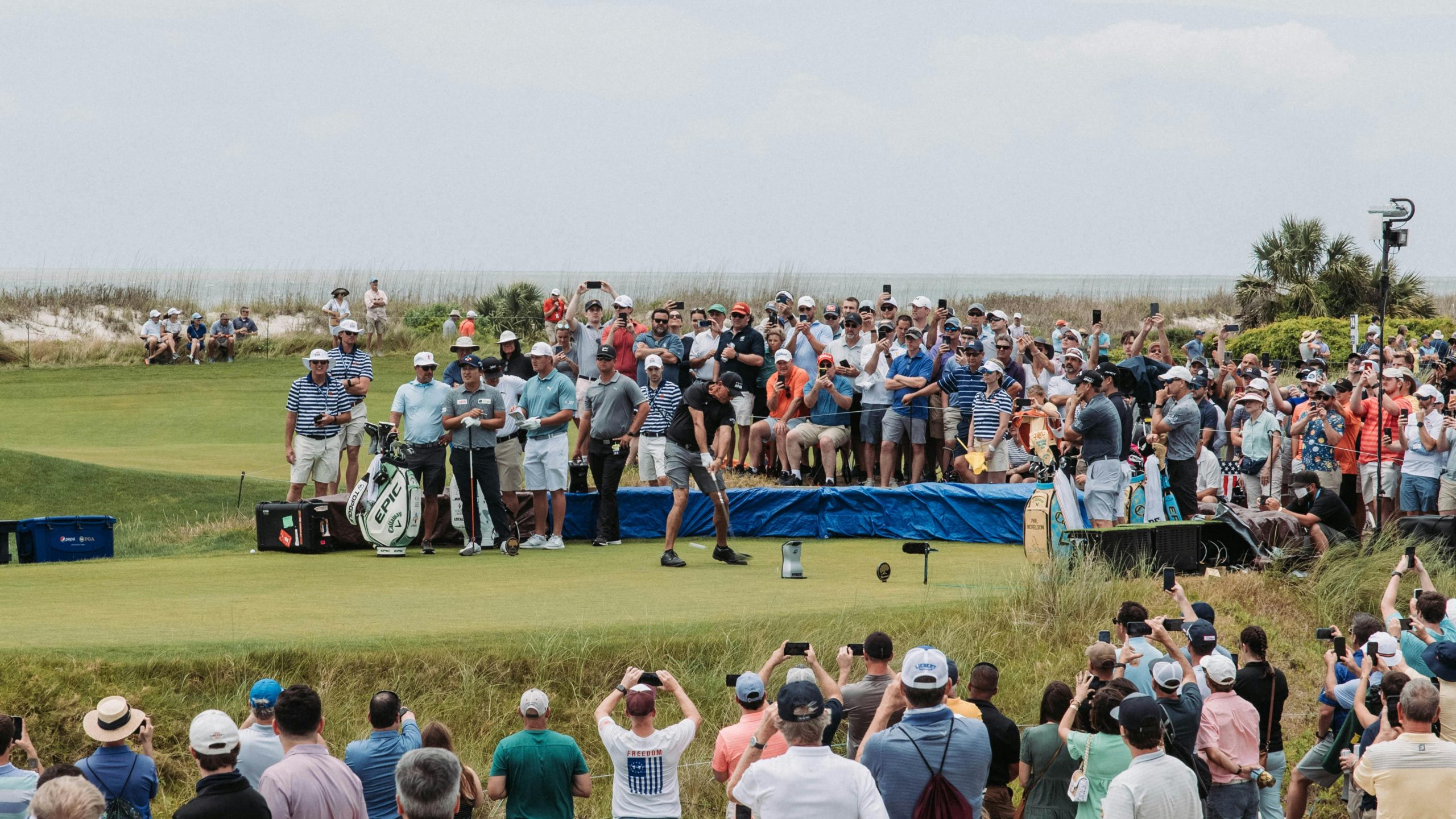 Golfeur frappant la balle devant une foule de spectateurs.