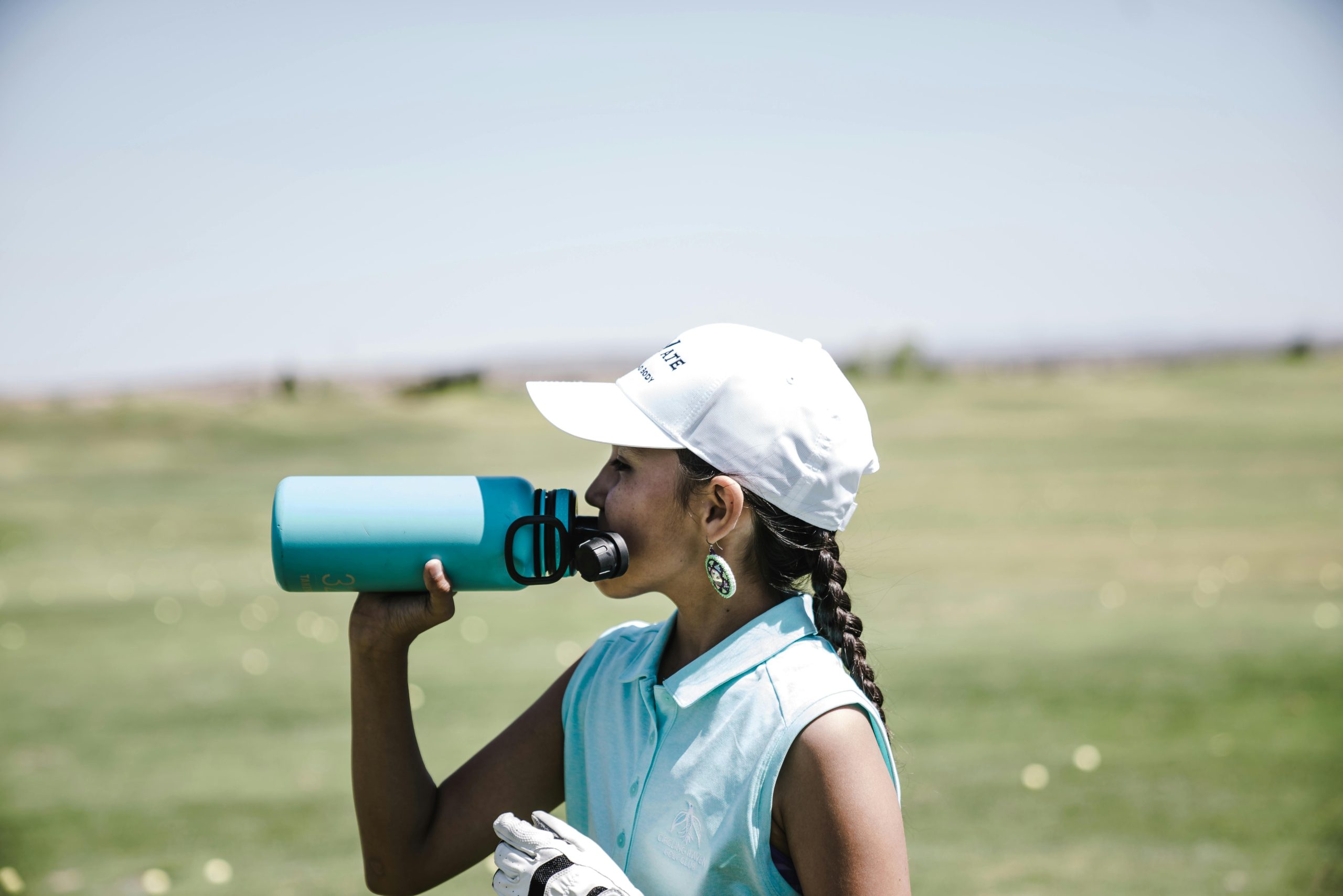 Jeune fille buvant de l'eau sur un terrain de golf.